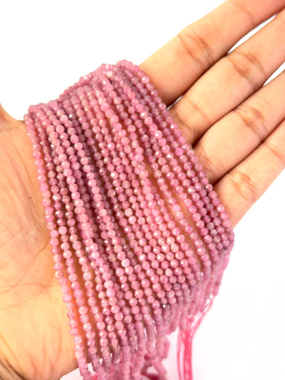 A person holds delicate strands of Pink Tourmaline beads, showcasing their faceted rondelle design.