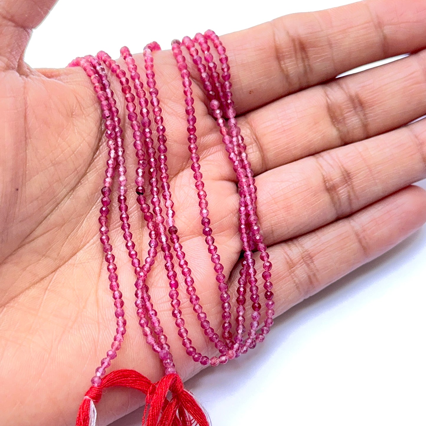 A person holds delicate strands of Pink Tourmaline beads, showcasing their smooth design.