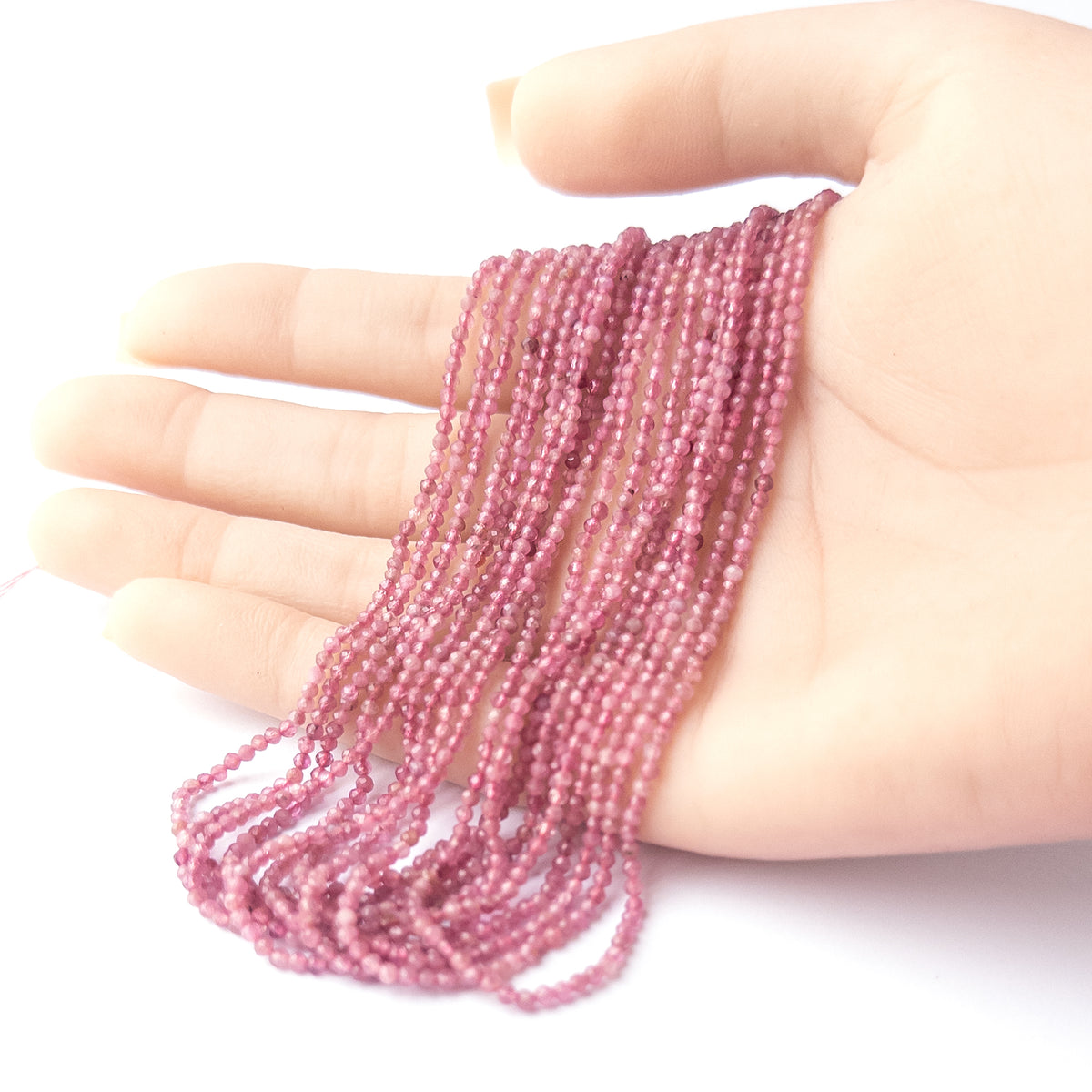 A person holds delicate strands of Pink Tourmaline beads, showcasing their faceted rondelle design.  