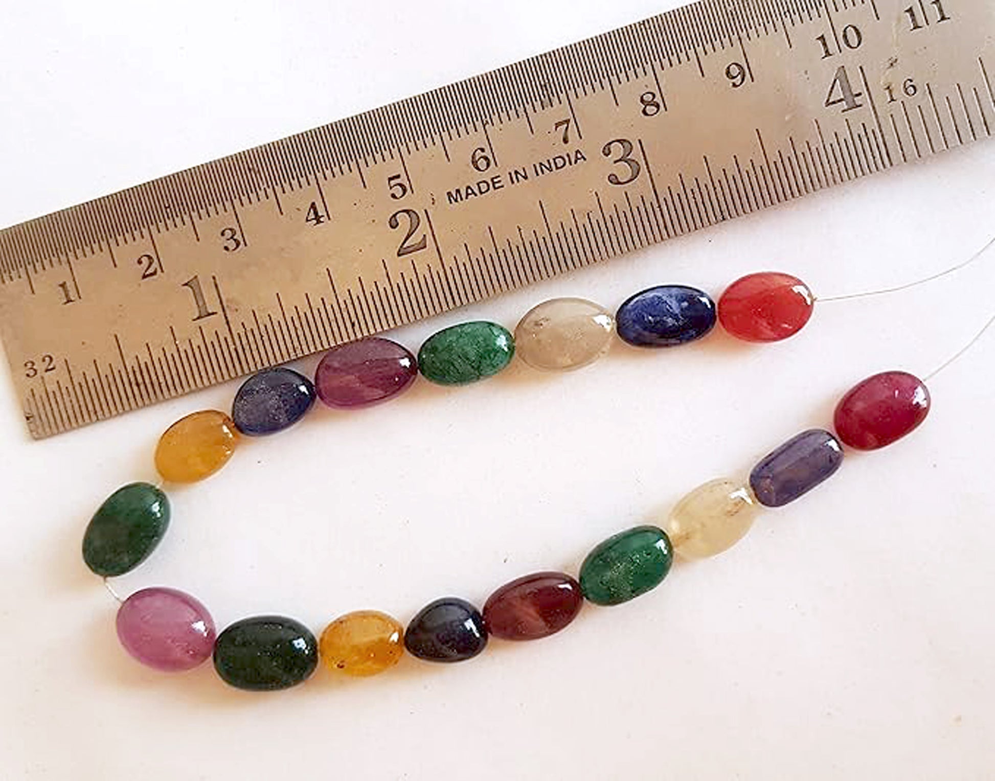   Close-up of a measuring ruler alongside a vibrant collection of precious gemstone beads.