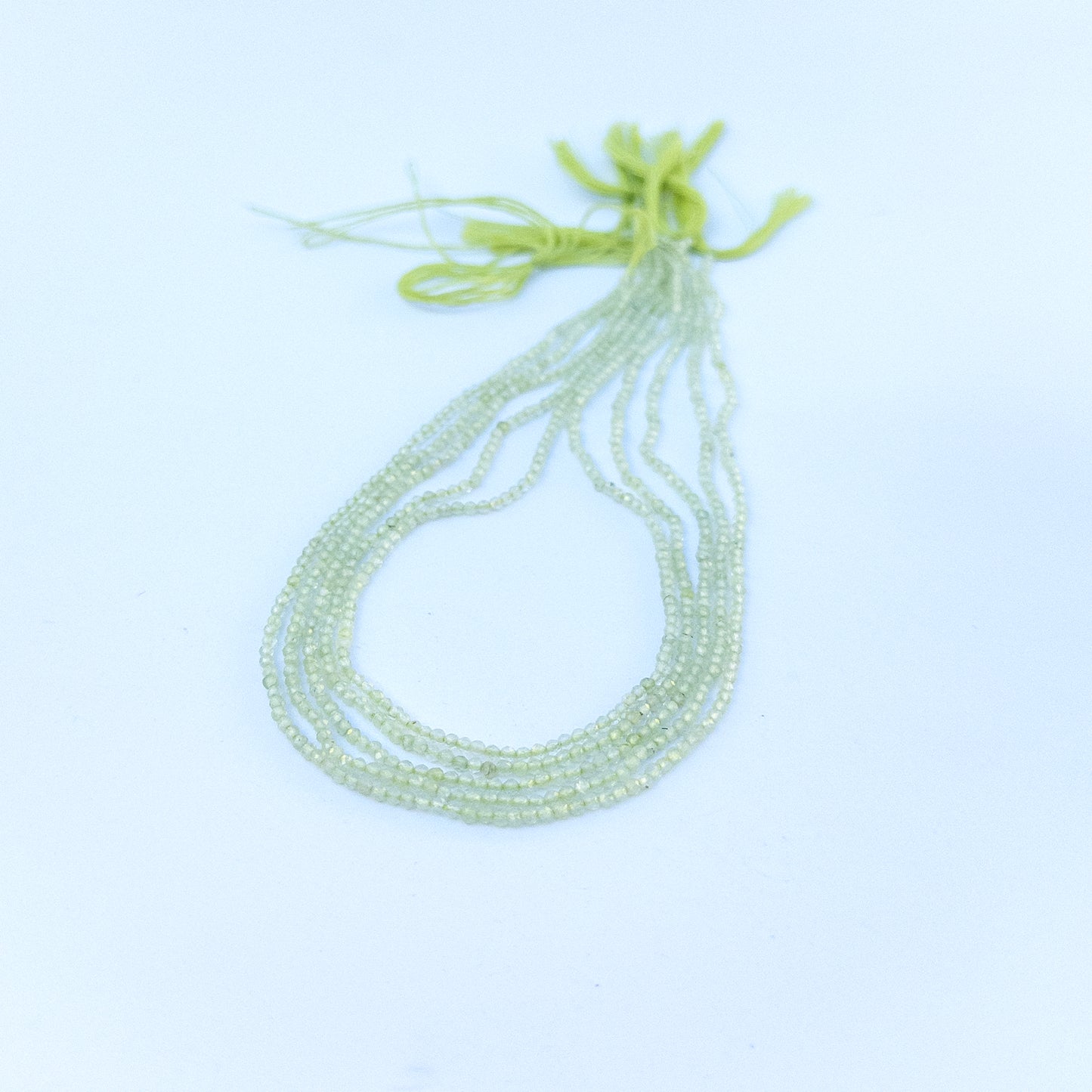 Prehnite faceted rondelle beads in 2.2mm size arranged in a strand, showing soft green tones for handmade jewellery components.