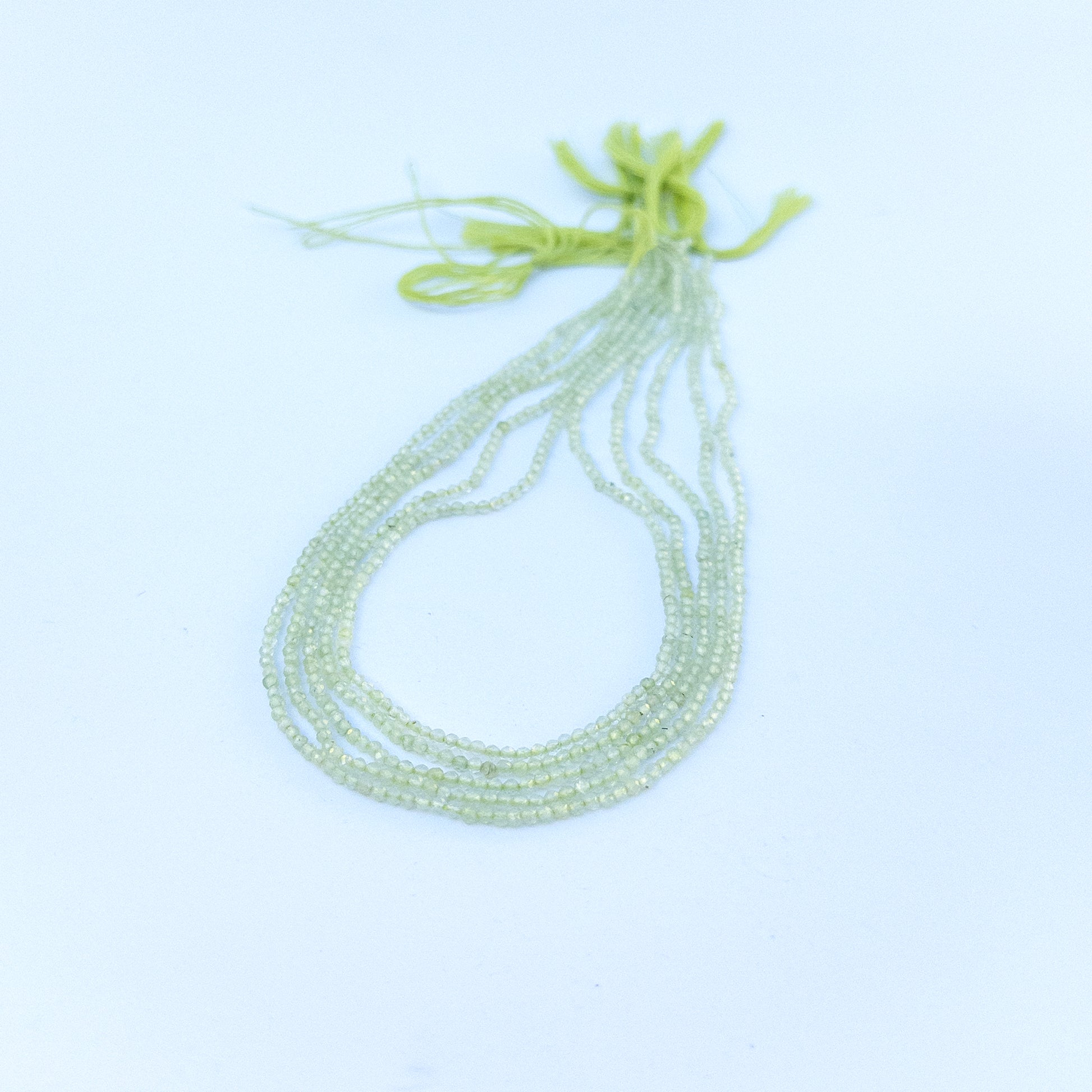 Prehnite faceted rondelle beads in 2.2mm size arranged in a strand, showing soft green tones for handmade jewellery components.