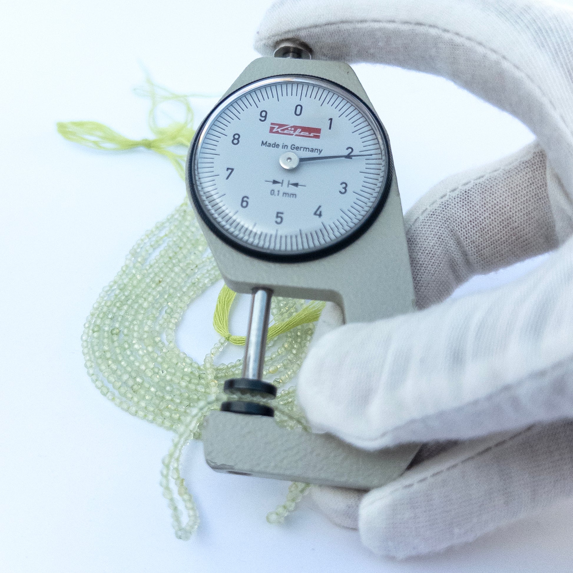 A dial gauge measures the Prehnite Faceted Rondelle 2.2mm gemstone.