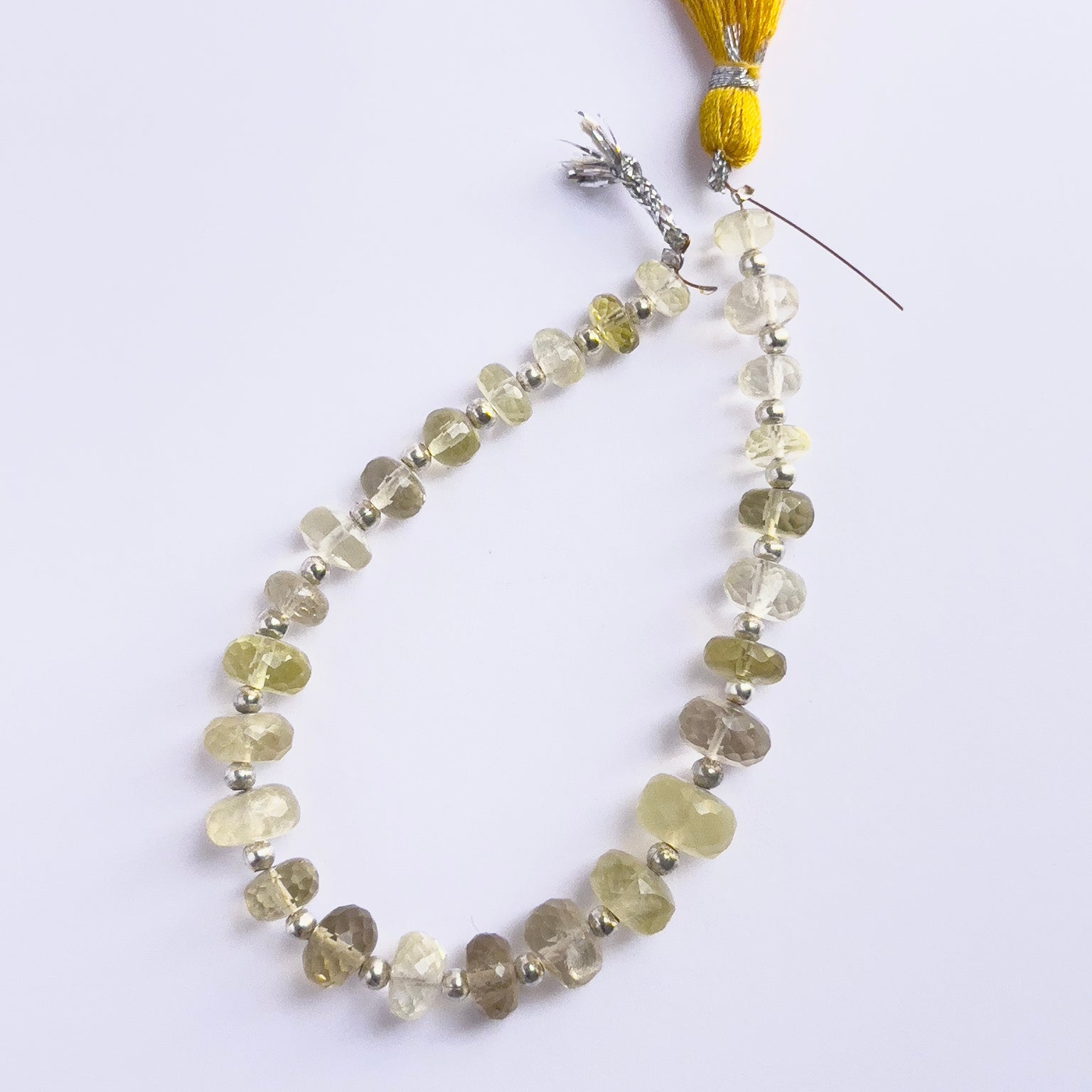 Close-up of natural gemstone beads showing the faceted rondelle cut and translucent green glow.