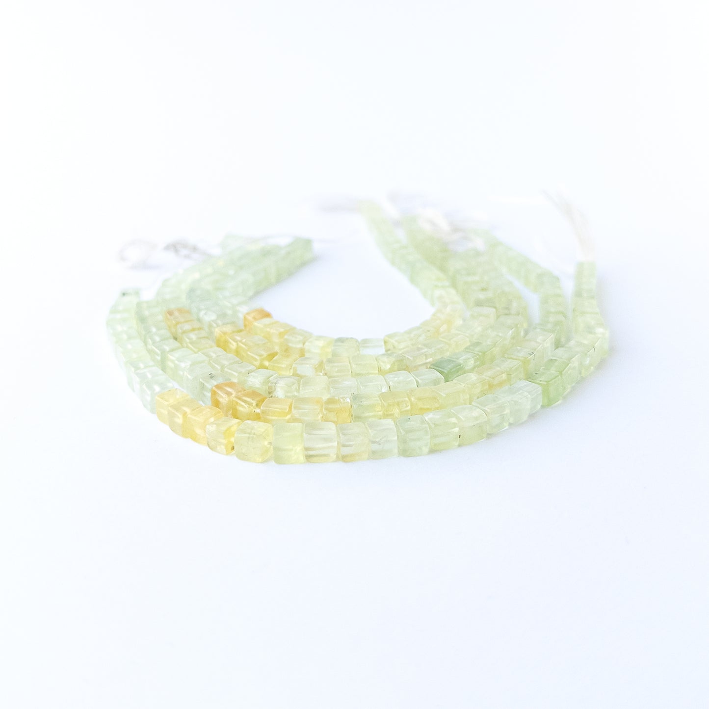Prehnite smooth cube gemstone beads in soft green tones arranged on a 20cm strand for handmade jewellery components.
