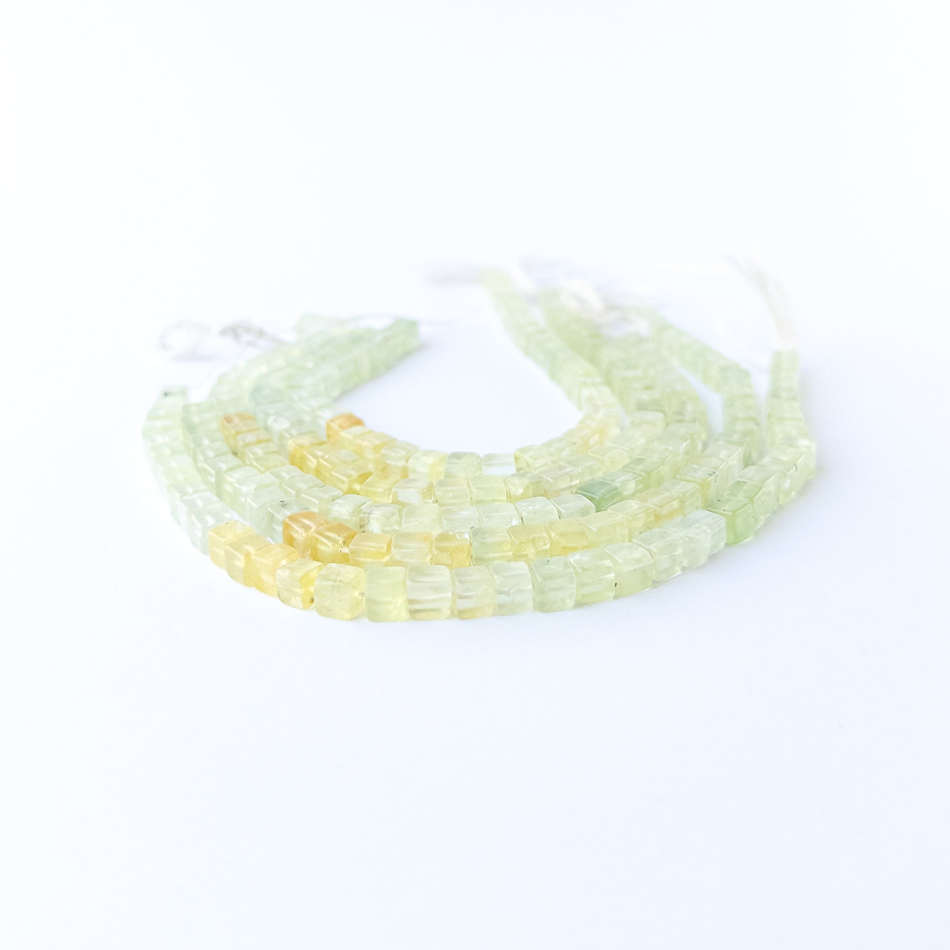 Prehnite smooth cube gemstone beads in soft green tones arranged on a 20cm strand for handmade jewellery components.