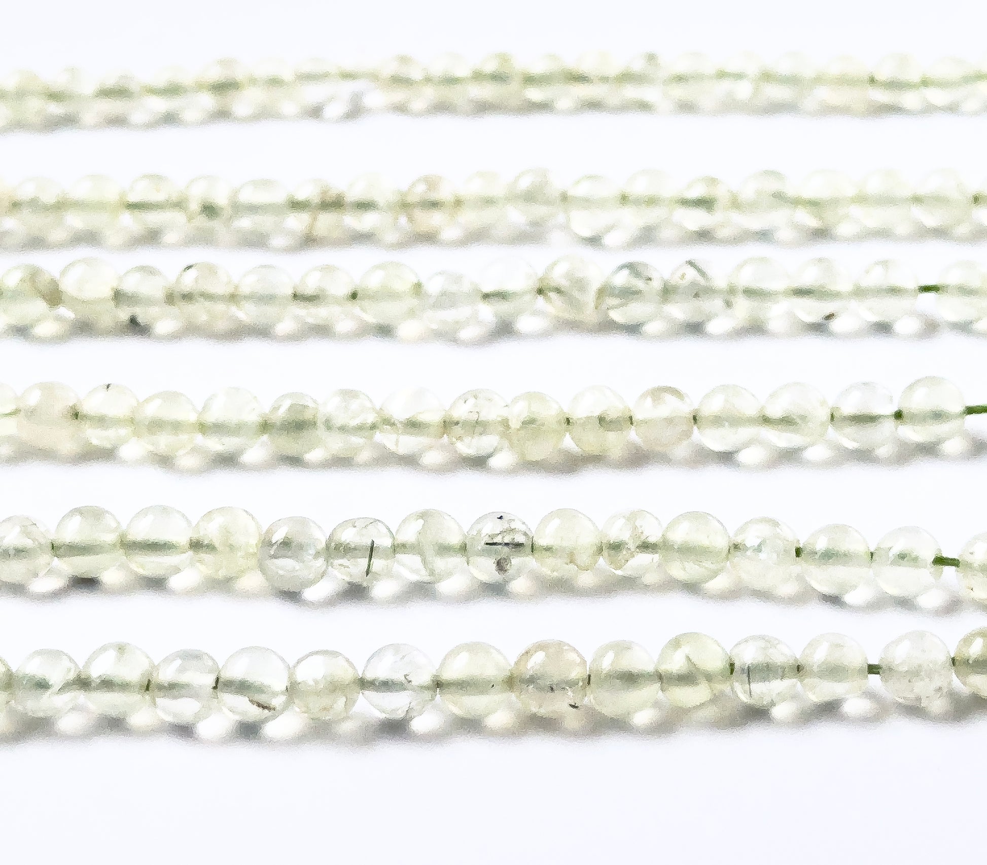Prehnite gemstones in smooth round form, offering a clean glossy finish and calming pale‑green tones.