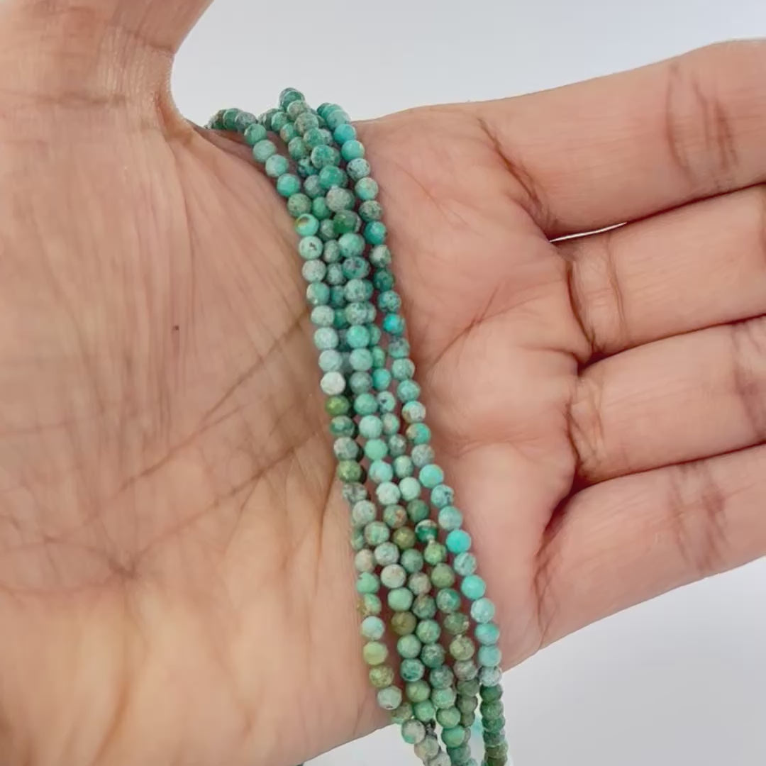 A video person holds delicate strands of Chrysocolla beads, showcasing their faceted rondelle design and sparkle.