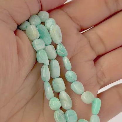 A video person holds delicate strands of Amazonite beads, showcasing their tumble‑smooth design and gentle shine.