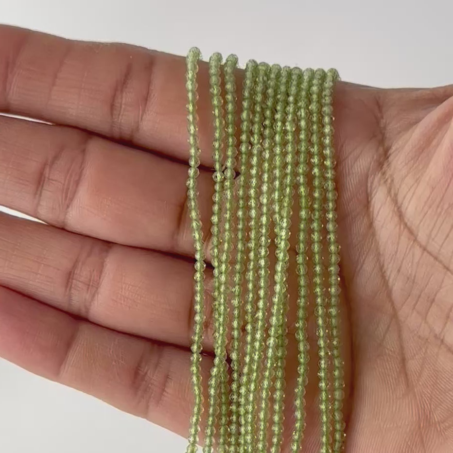  A video person holds delicate strands of Peridot beads, showing their faceted rondelle sparkle.