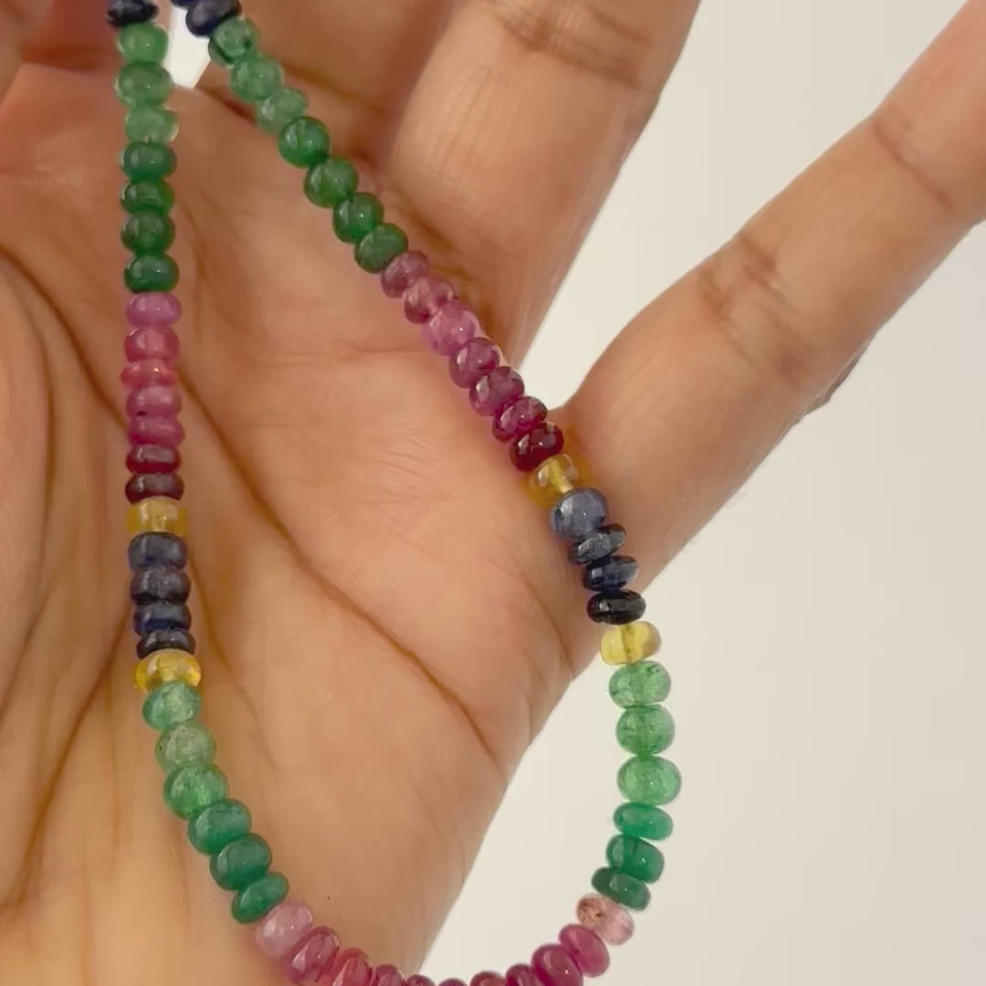 A person holds delicate strands of Multi Precious beads, showcasing their smooth design.