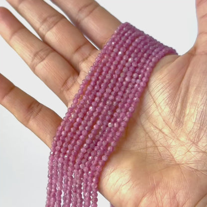 A video person holds delicate strands of Pink Tourmaline beads, showcasing their faceted rondelle design and sparkle.