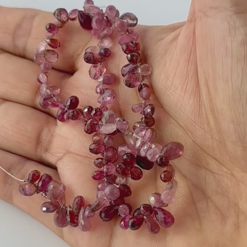 Faceted pink tourmaline teardrop beads with glossy brilliance, arranged neatly on a strand for jewellery making.