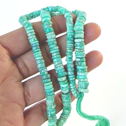 A video person holds delicate strands of Amazonite beads, showcasing their smooth wheel design and sparkle.