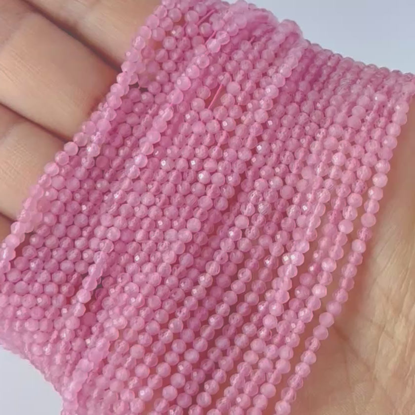 A video person holds delicate strands of Pink Quartz beads, showcasing their faceted rondelle design and sparkle