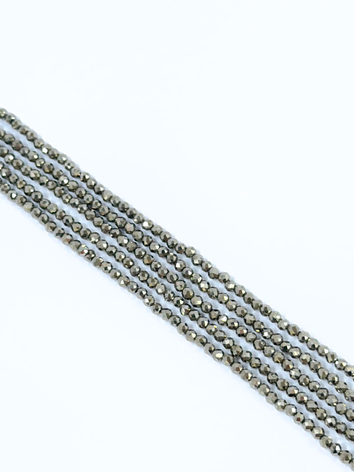 Close‑up of Pyrite stone beads arranged in a strand with reflective surfaces.