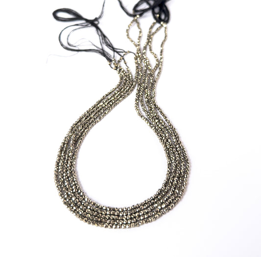 Pyrite faceted rondelle gemstone beads in metallic gold tones arranged on a strand for handmade jewellery components.