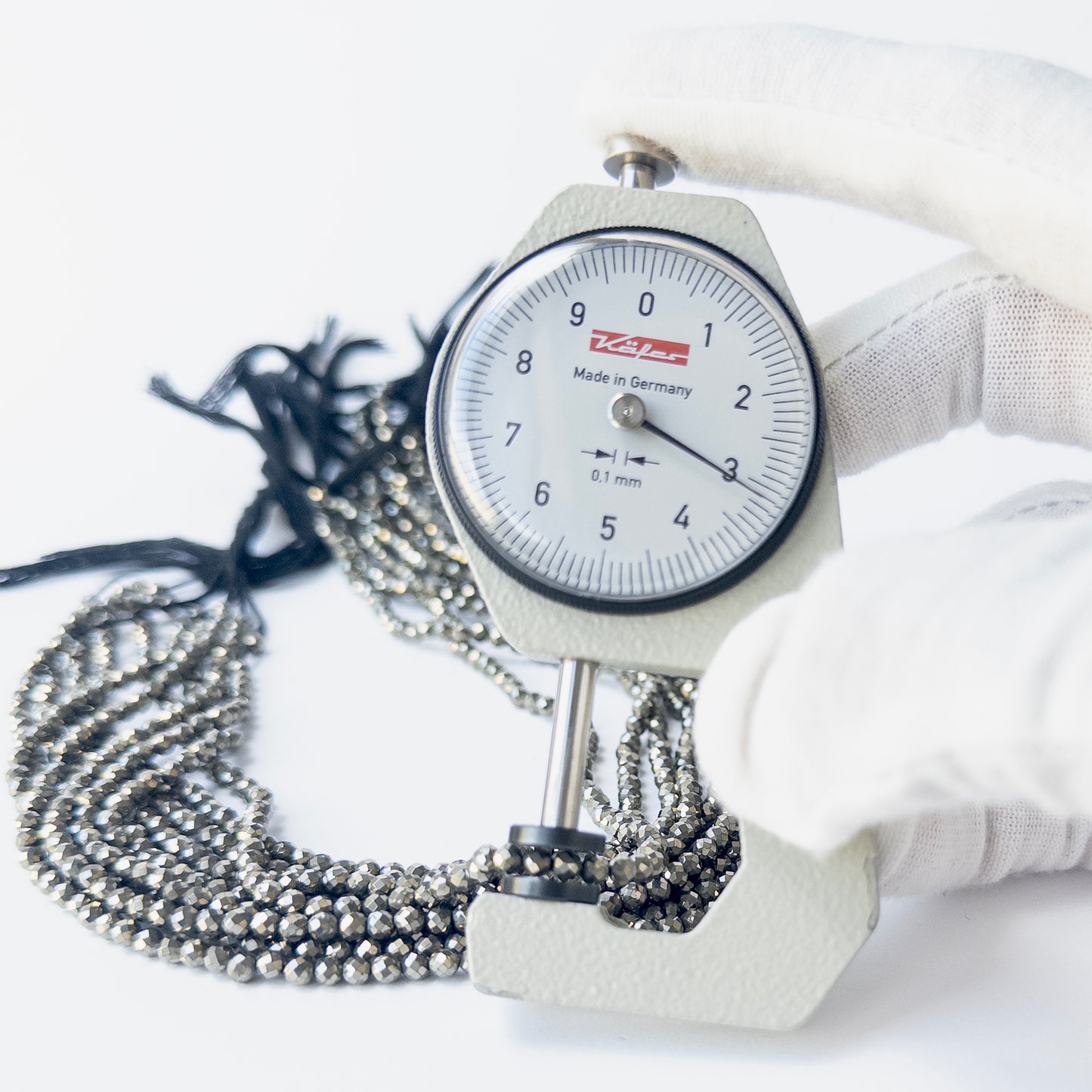 A dial gauge measures the Pyrite faceted rondelle 3.1mm gemstone.