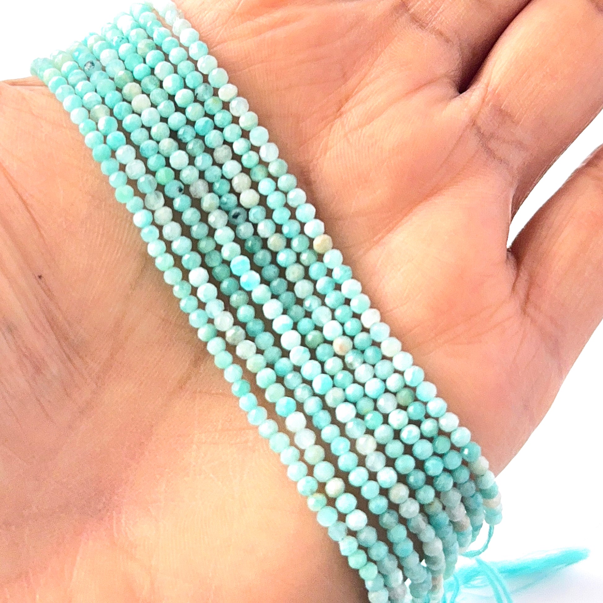 A person holds delicate strands of Amazonite beads, showcasing their faceted rondelle design.