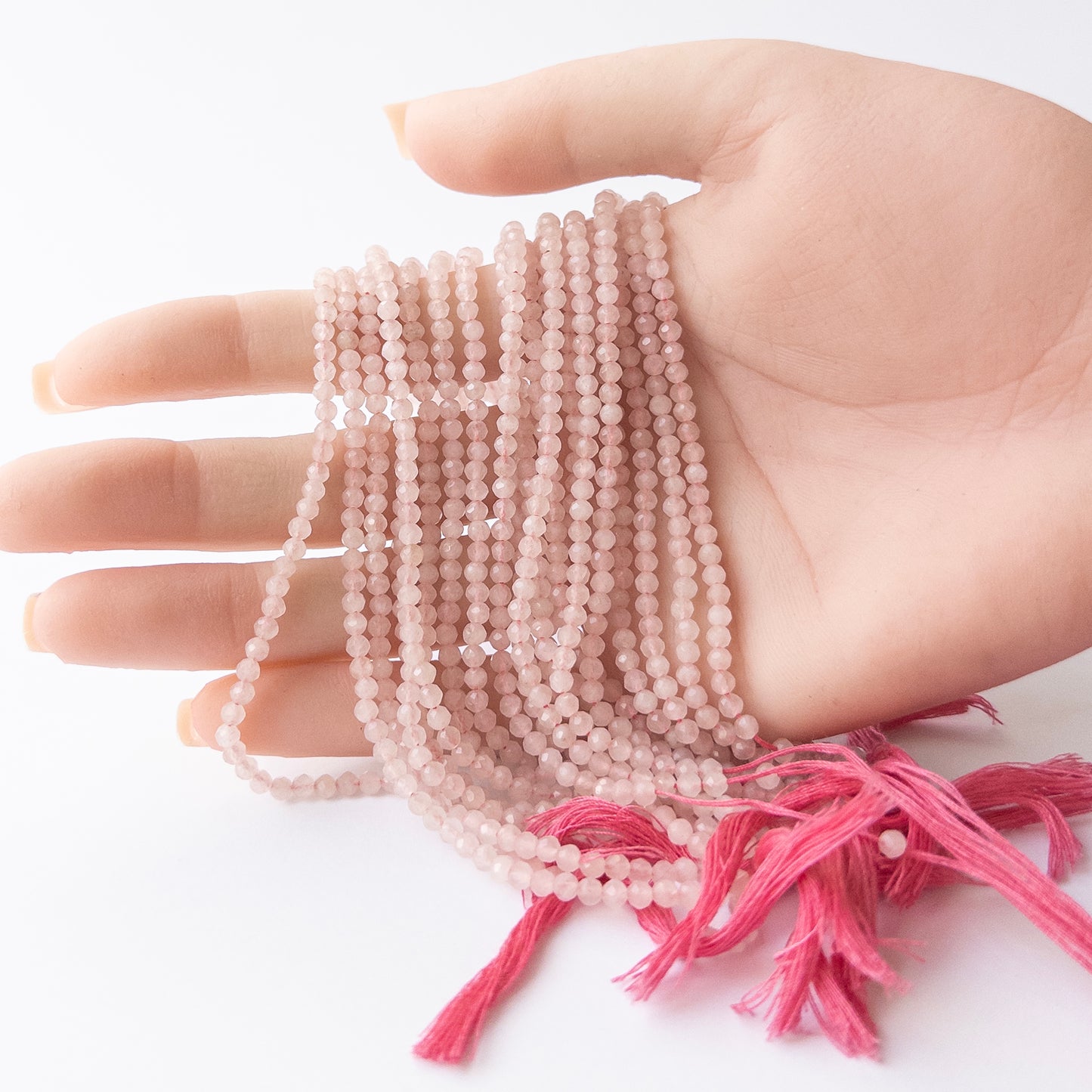 A person holds delicate strands of Quartz beads, showcasing their faceted rondelle design.