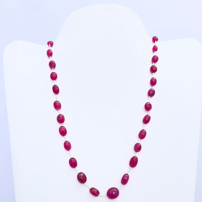 Quartz necklace with smooth oval beads in deep pink tones arranged on a white bust stand.