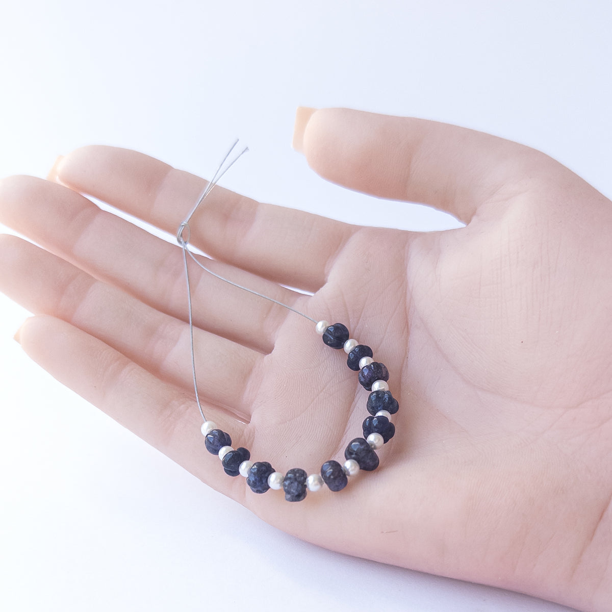 A person holds delicate strands of Quartz beads, showcasing their pumpkin cut design.