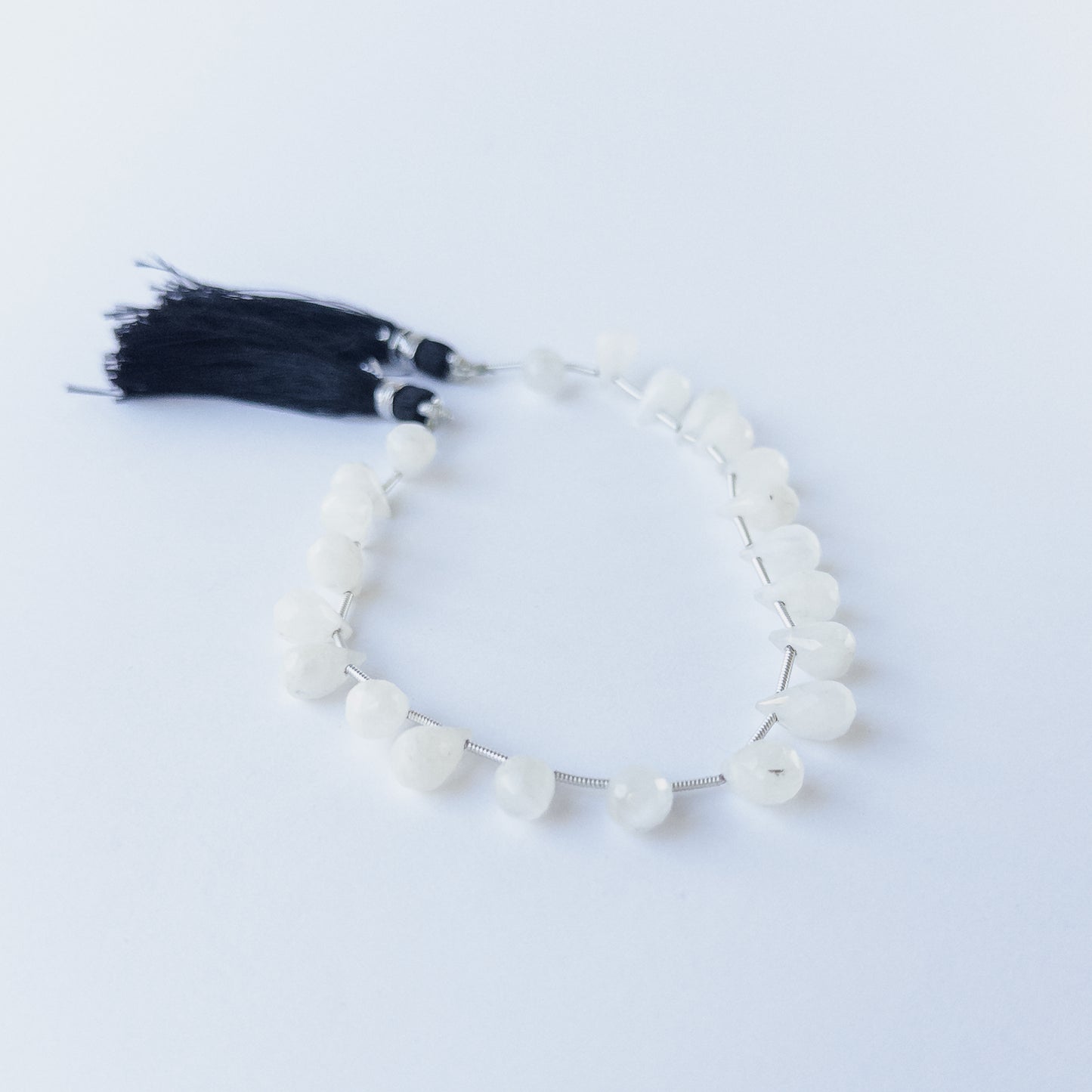 Authentic Rainbow Moonstone gemstone beads with faceted briolette cut arranged neatly in a small 17‑piece set.