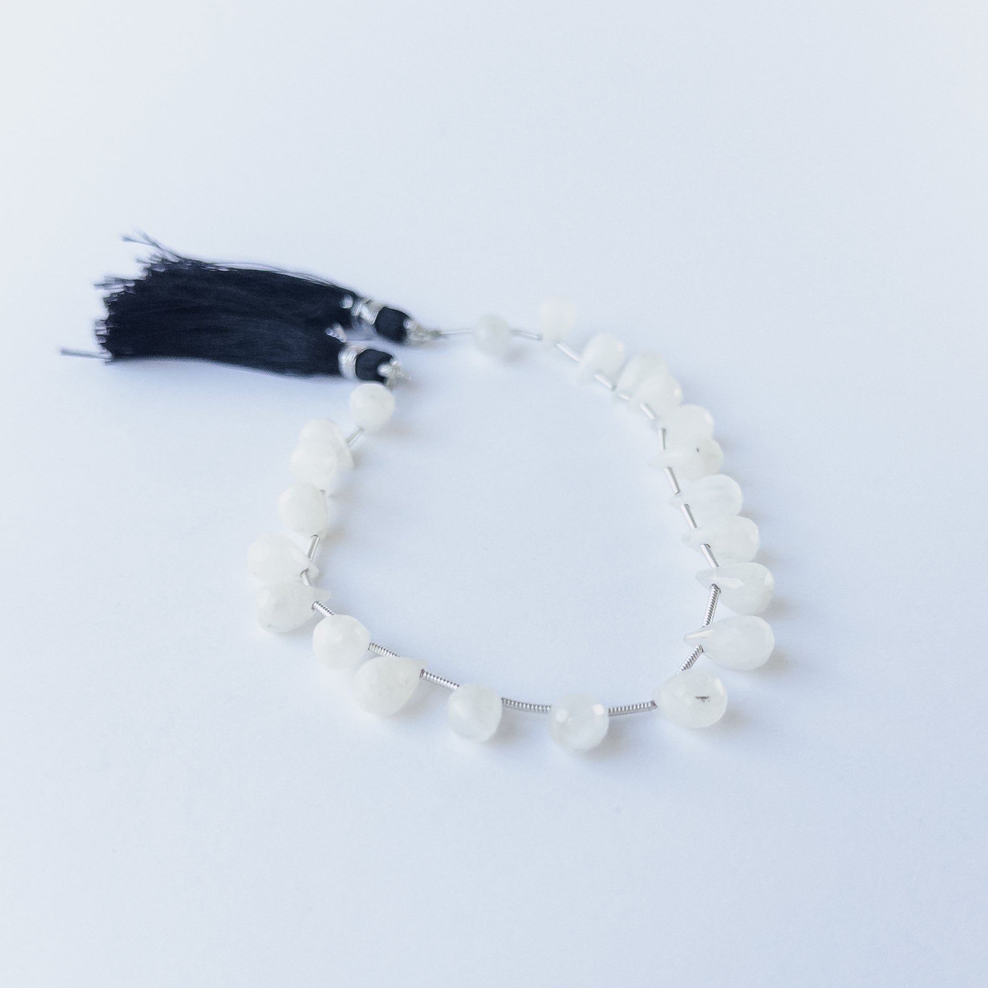 Authentic Rainbow Moonstone gemstone beads with faceted briolette cut arranged neatly in a small 17‑piece set.
