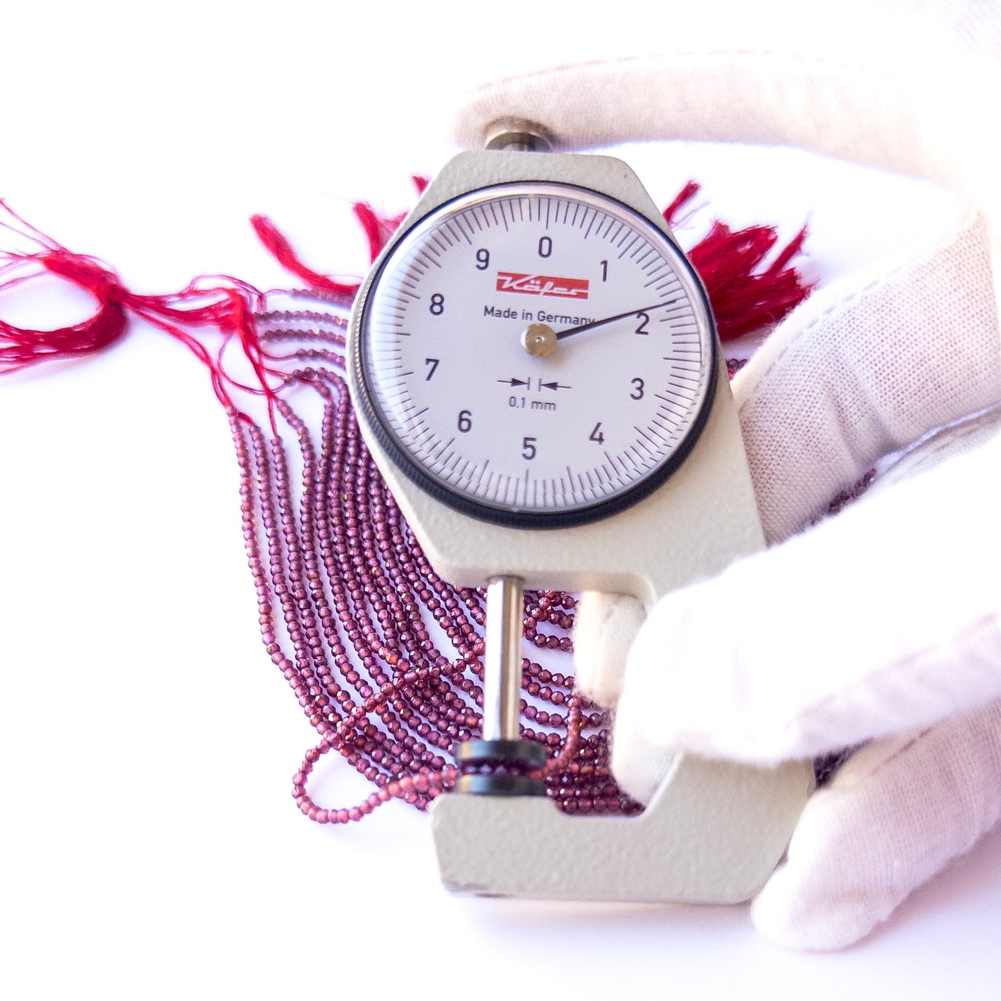 A dial gauge measures the Rhodolite Garnet faceted rondelle 1.9mm gemstone.