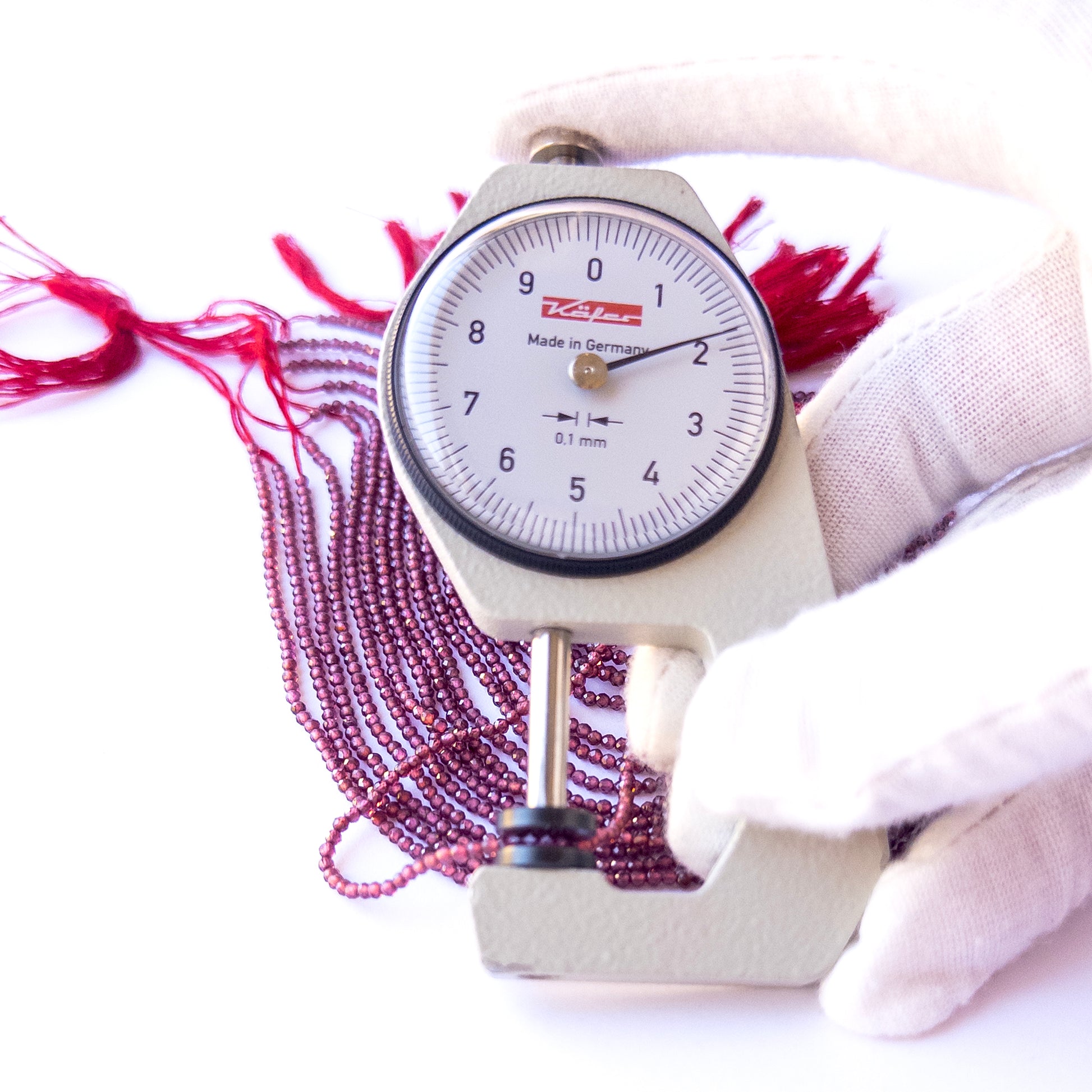 A dial gauge measures the Rhodolite Garnet faceted rondelle 1.9mm gemstone.