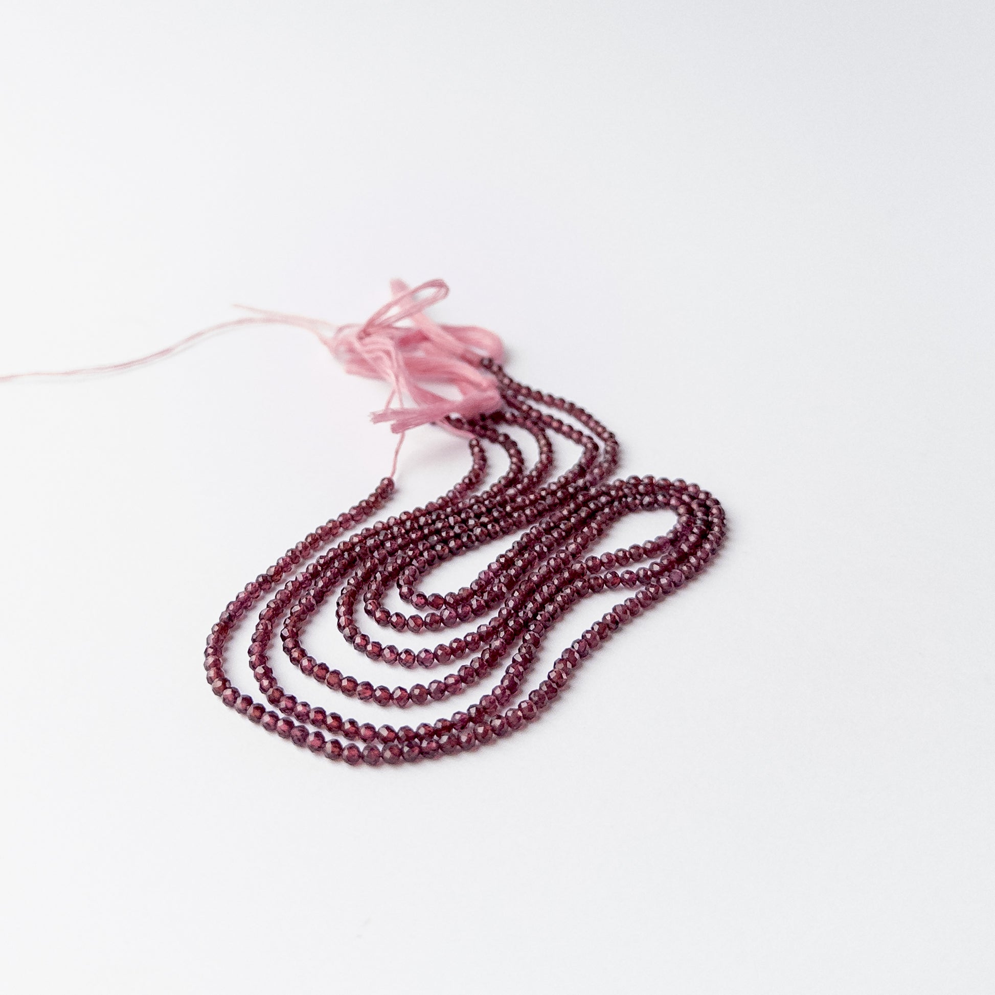 Close up of Rhodolite Garnet faceted rondelle beads highlighting clarity, cut and lustrous finish.