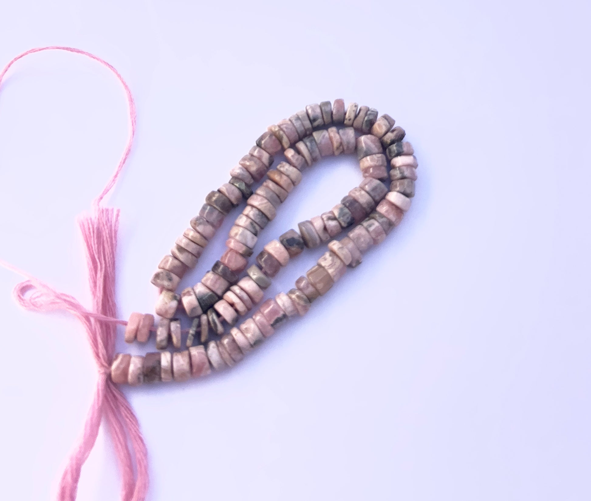Handmade jewellery components featuring smooth wheel Rhodonite beads with soft pink tones.
