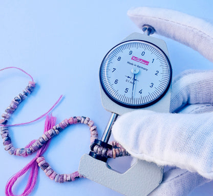 A dial gauge measures the Rhodonite smooth wheel 4.5mm gemstone.