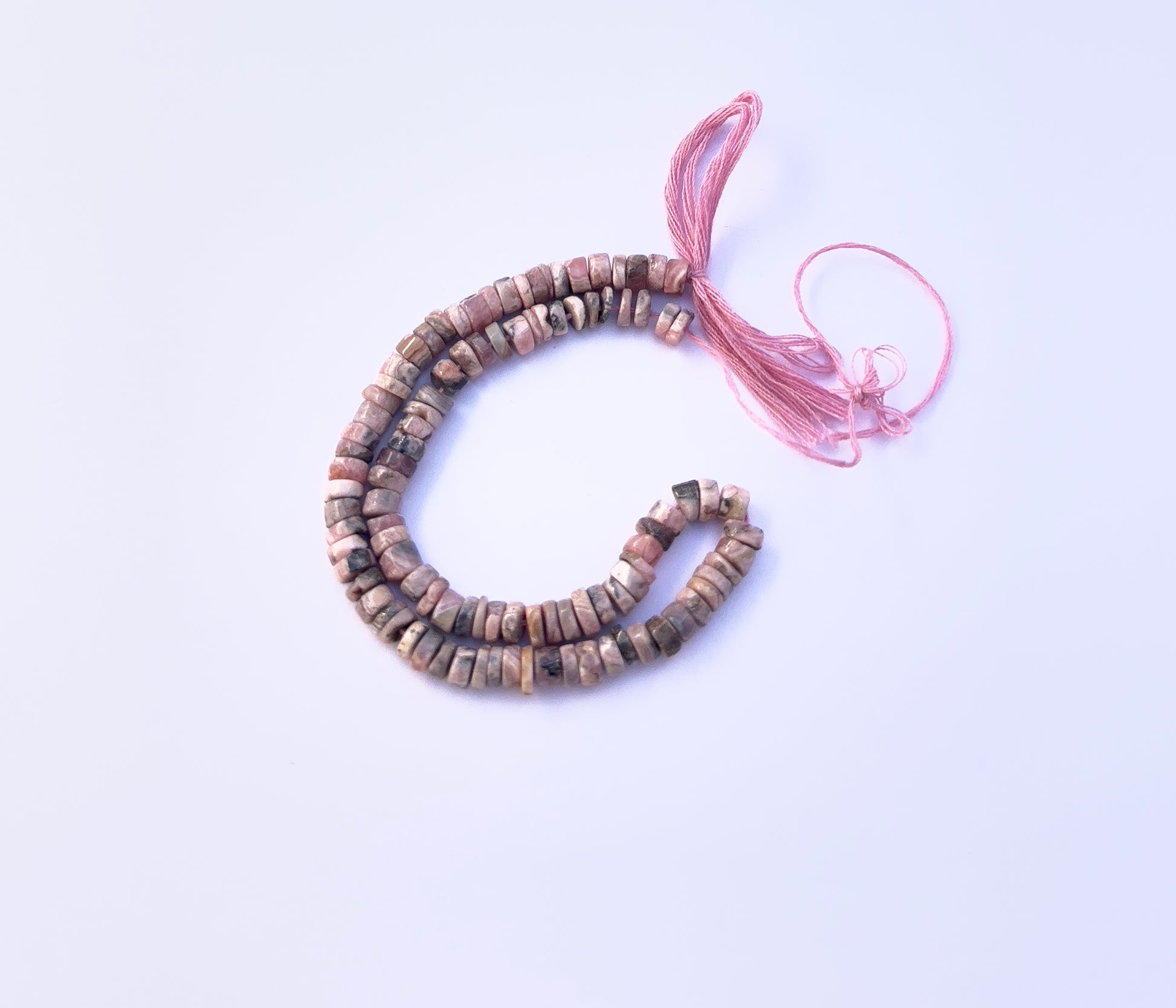 Natural gemstone beads in Rhodonite arranged neatly to highlight colour and craftsmanship.