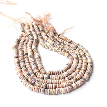 Rhodonite smooth wheel heishi gemstone beads arranged in a strand showing soft pink tones and polished finish.