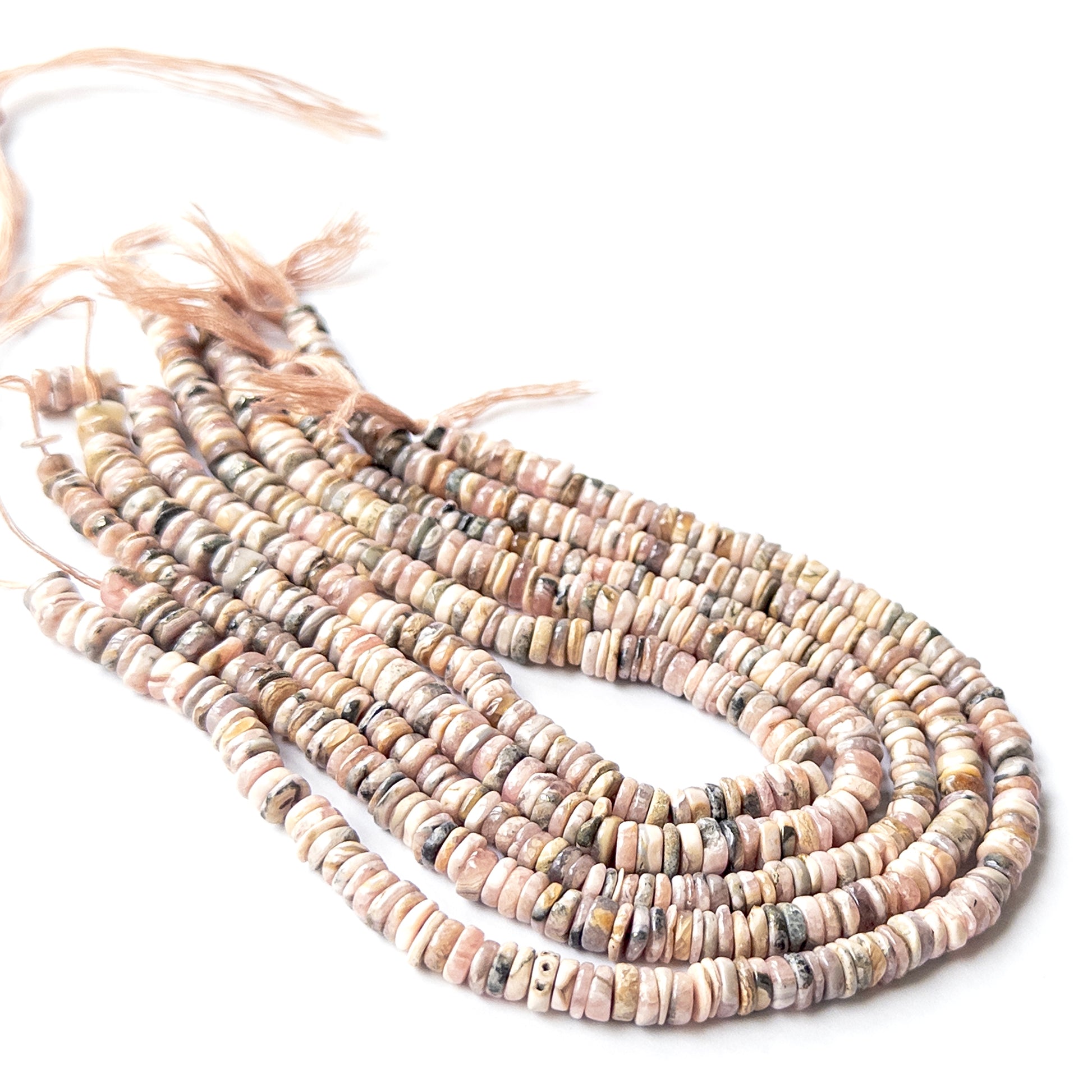 Close‑up of genuine Rhodonite wheel heishi stone beads with clean shaping and warm pink colour.