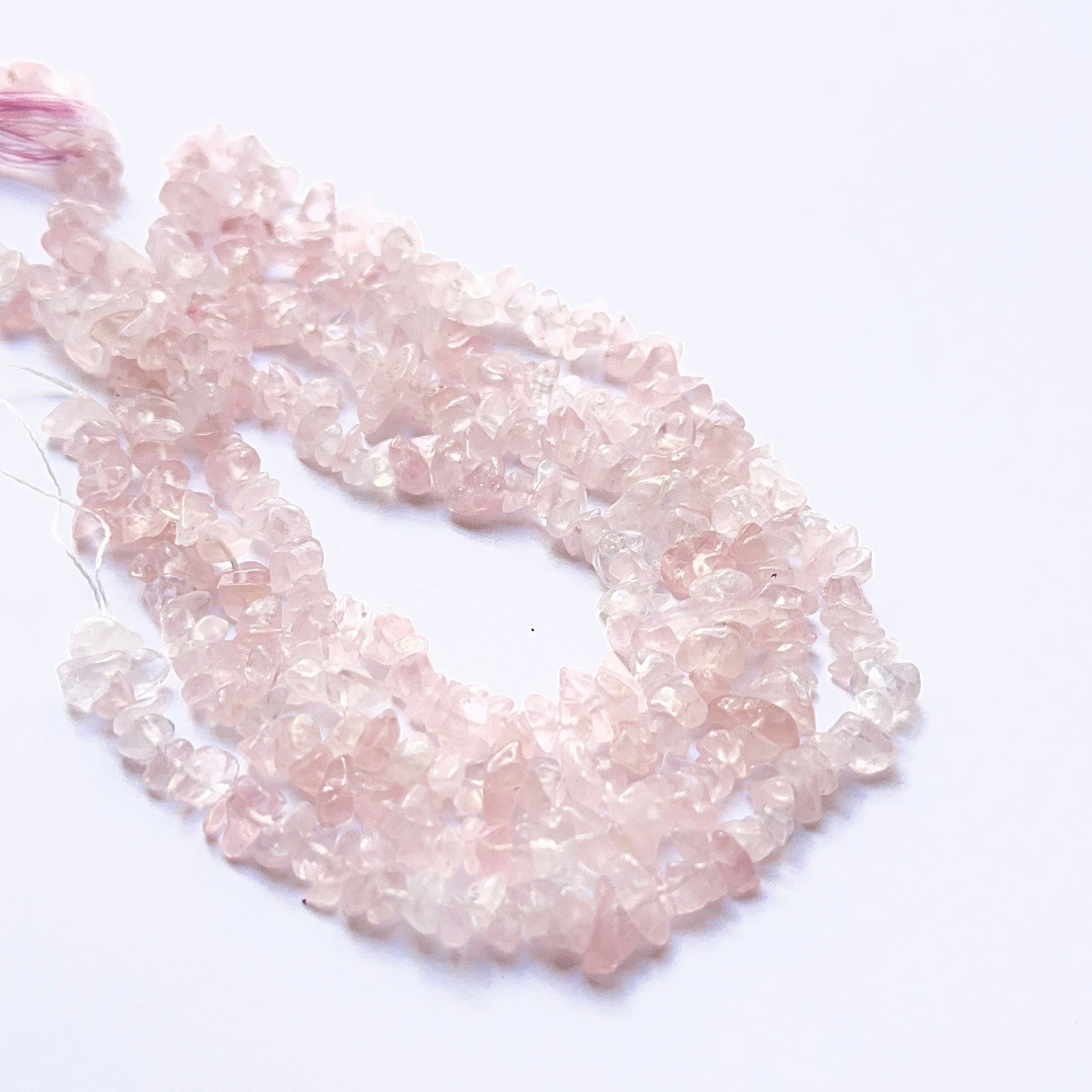 Handmade jewellery components featuring rose quartz chips with varied shapes and polished surfaces.