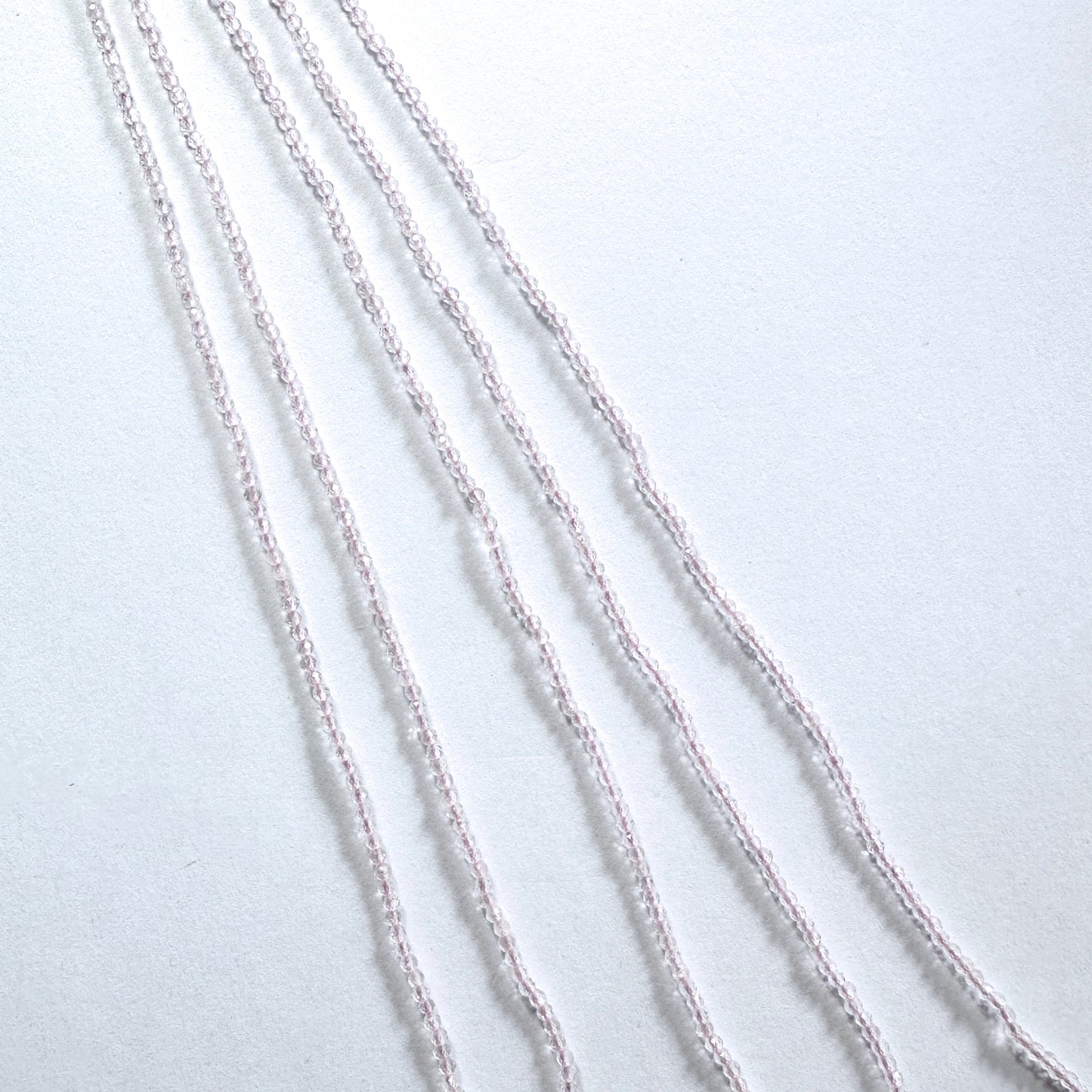 Rose Quartz gemstone beads in faceted rondelle cut reflect soft light across the strand.