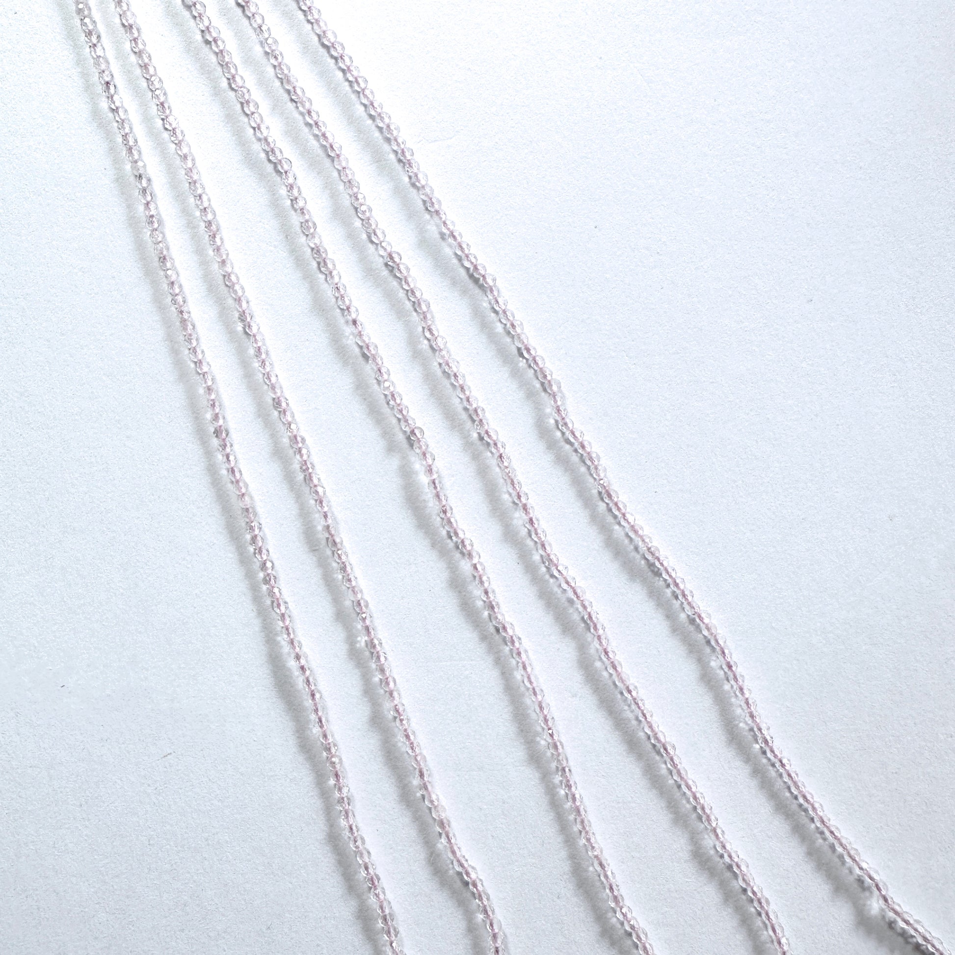 Rose Quartz gemstone beads in faceted rondelle cut reflect soft light across the strand.