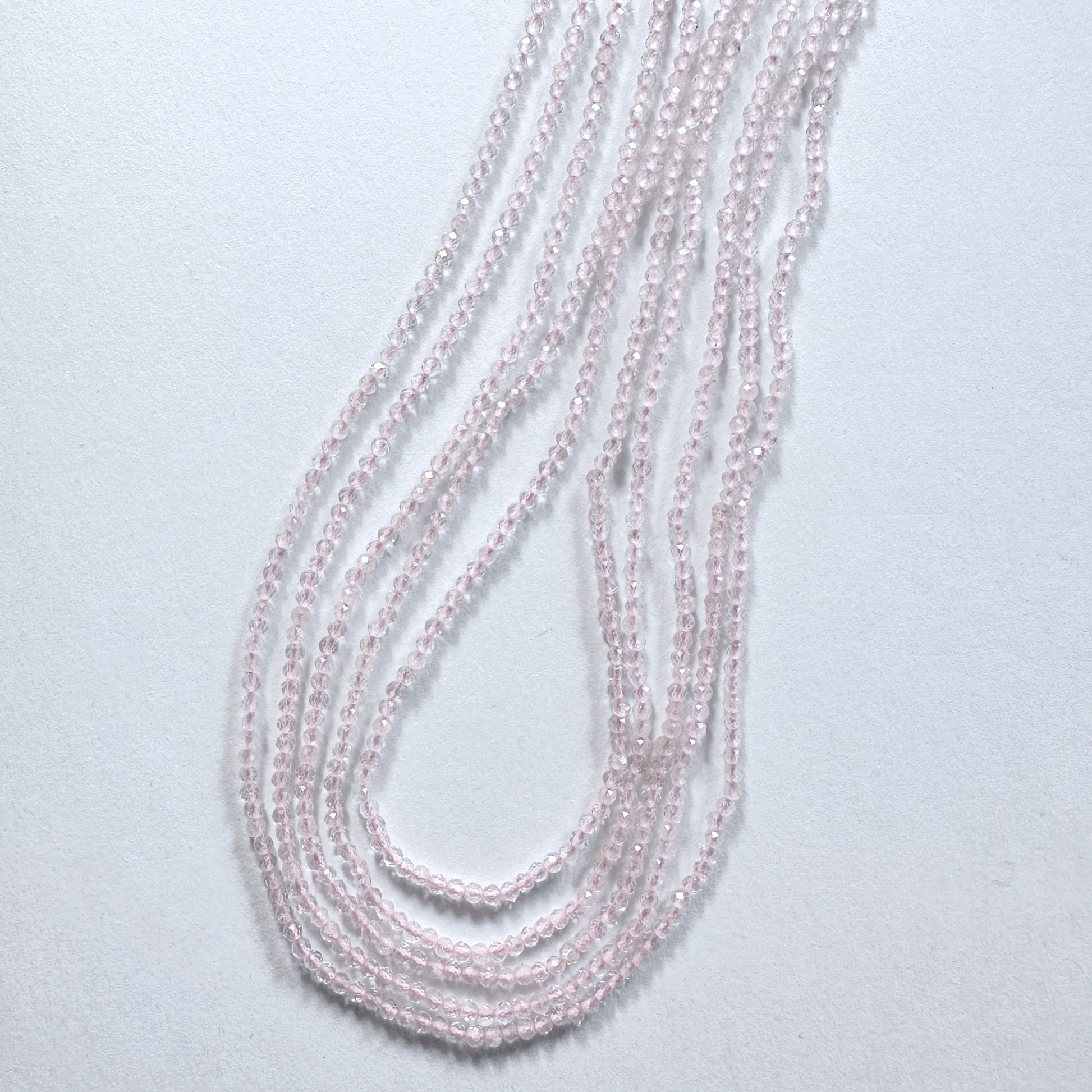 Delicate strands of Rose Quartz beads, showcasing their faceted design.