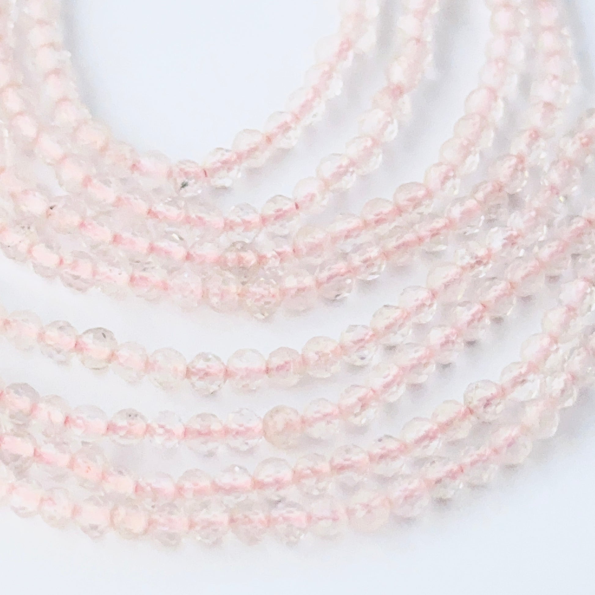 Faceted rondelle Rose Quartz beads arranged neatly, highlighting their polished finish and handmade jewellery component quality