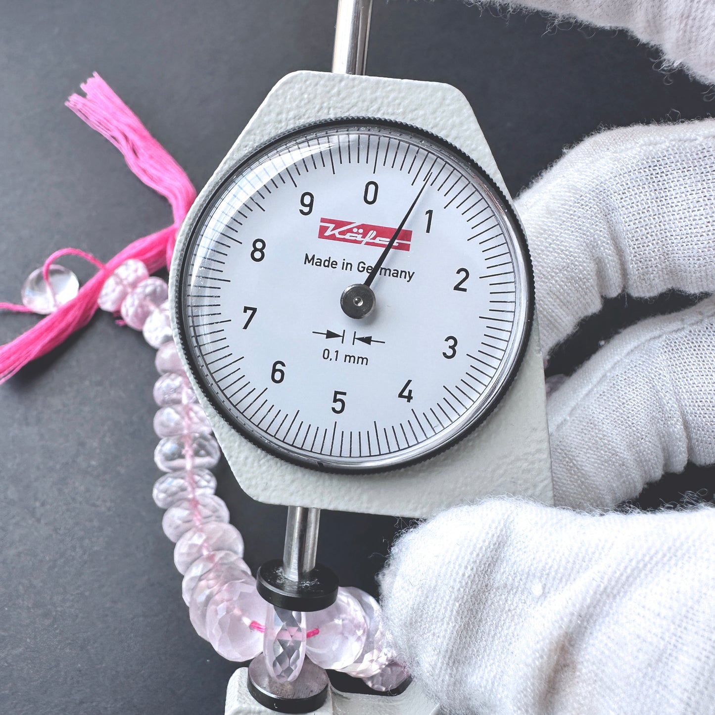 A dial gauge measures the Rose Quartz micro faceted rondelle 10-10.5mm gemstone.