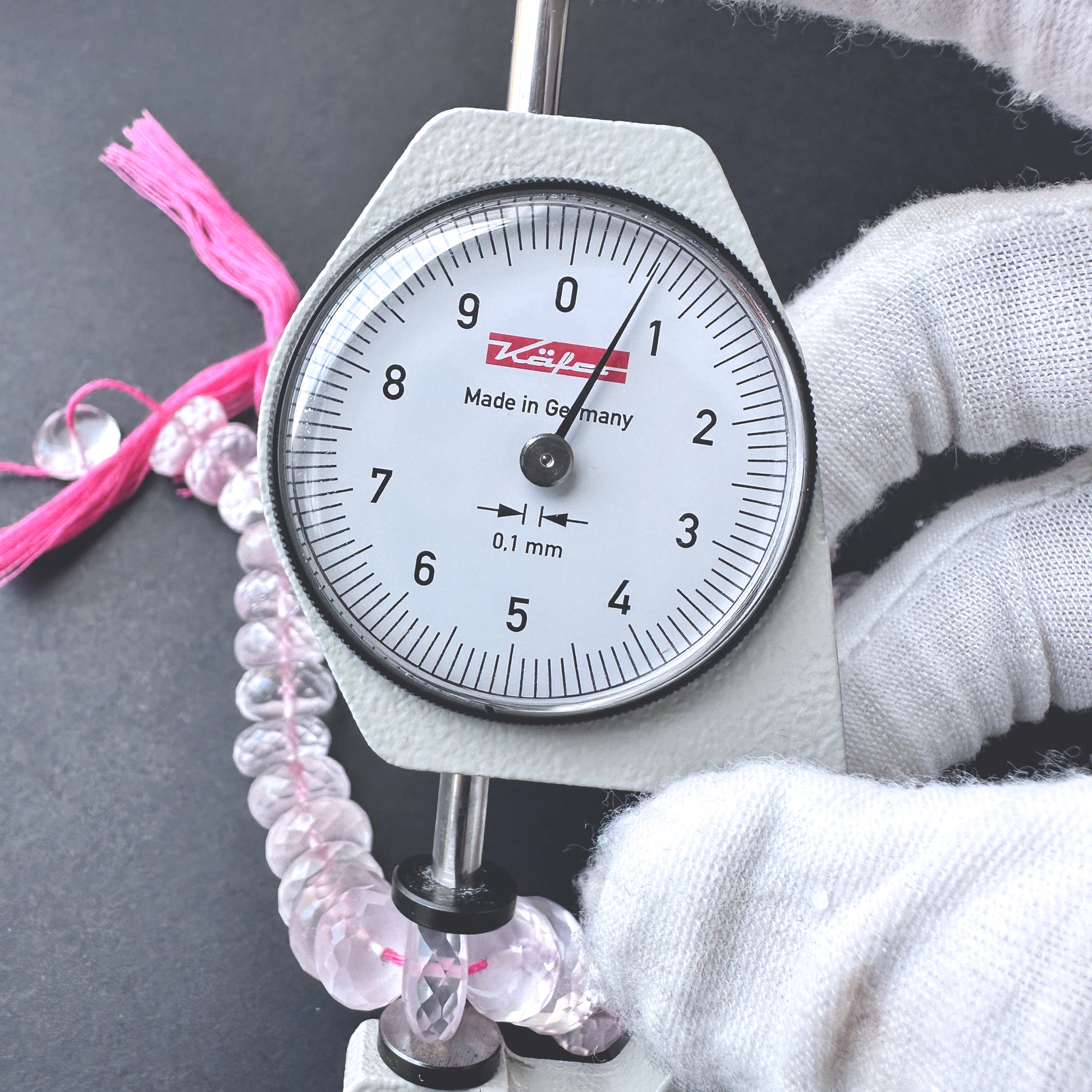 A dial gauge measures the Rose Quartz micro faceted rondelle 10-10.5mm gemstone.