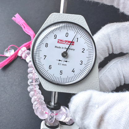 A dial gauge measures the Rose Quartz micro faceted rondelle 10-10.5mm gemstone.
