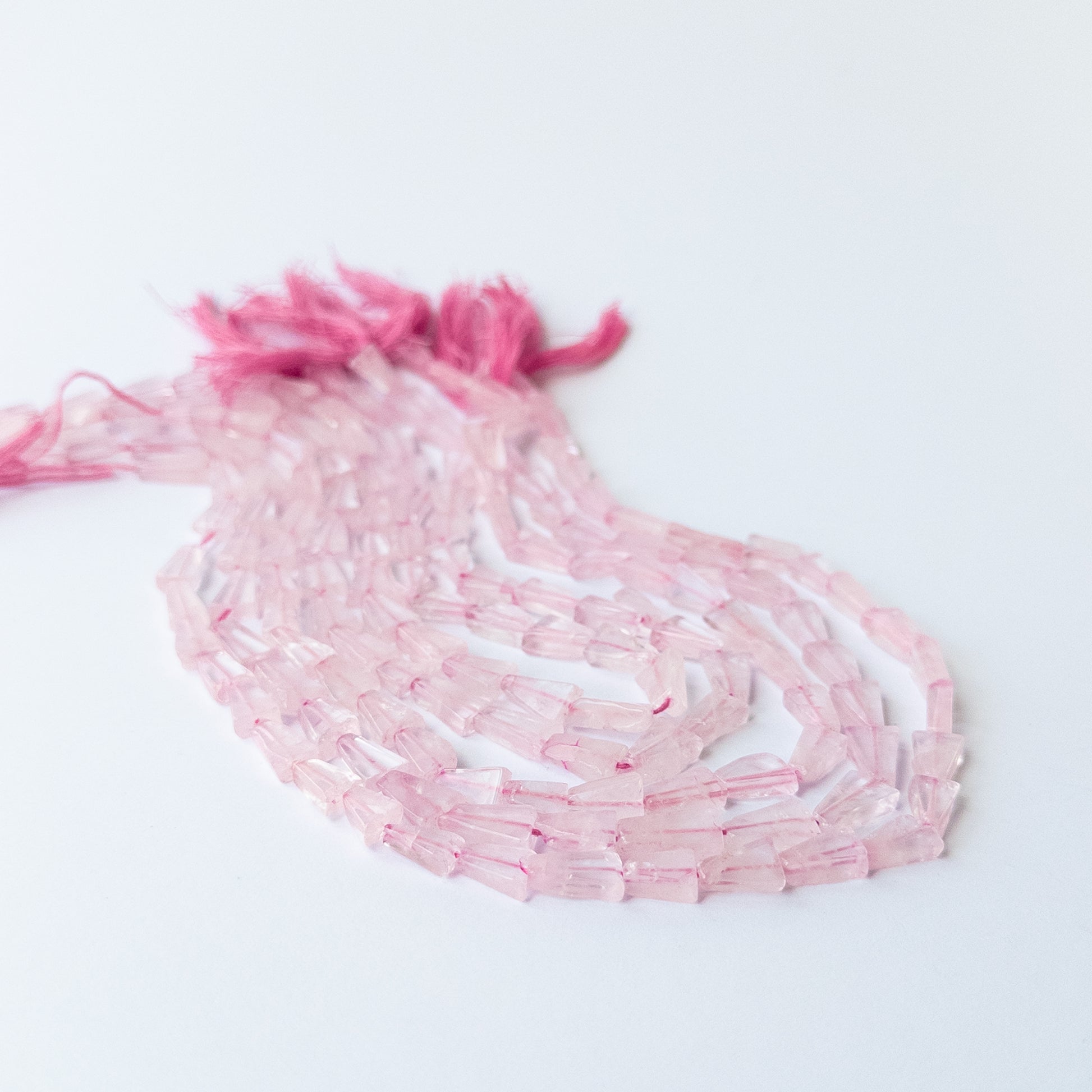Close‑up of natural Rose Quartz gemstone beads in tapered rectangle shape with gentle rosy shine.