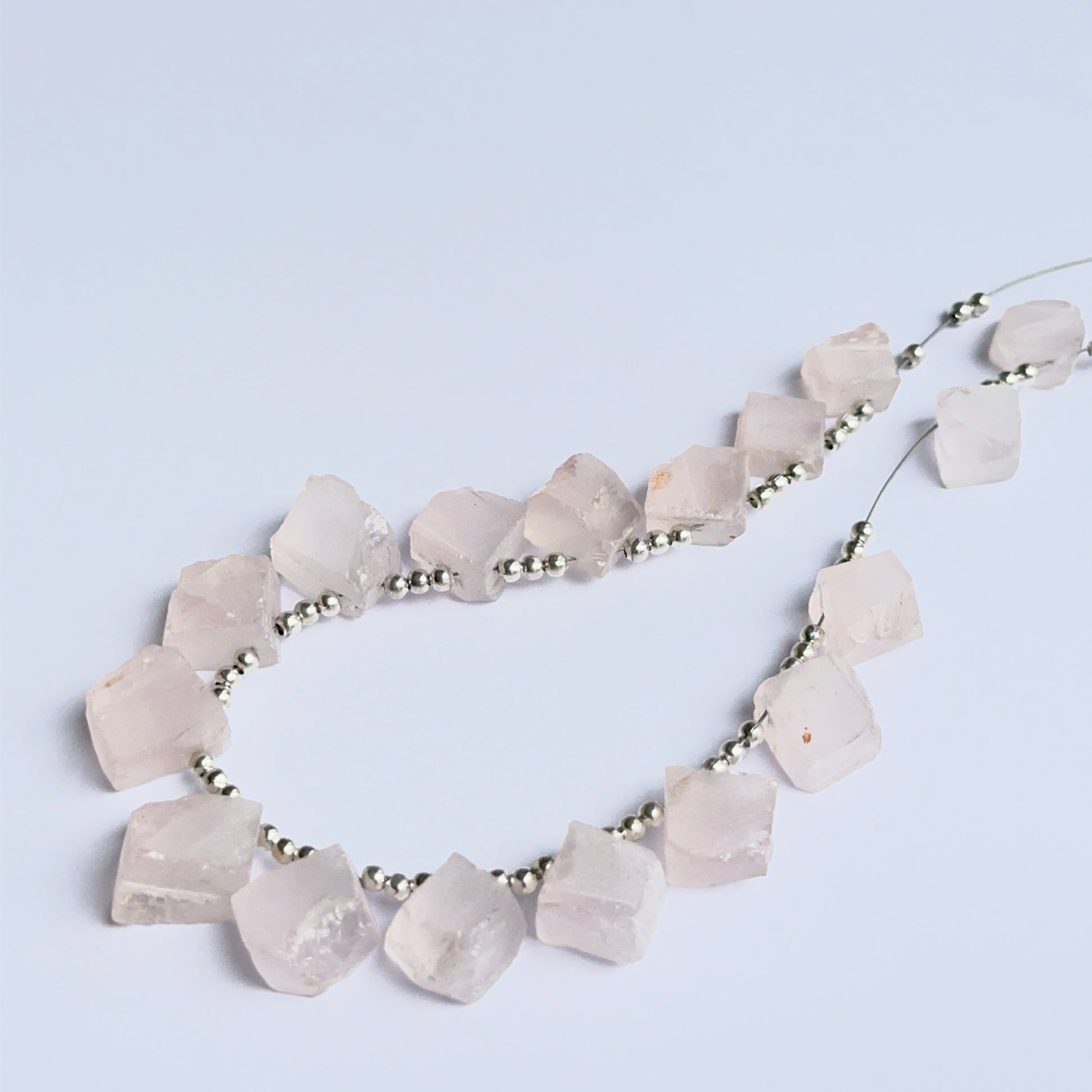 Raw rose quartz beads displayed with visible texture ideal for natural gemstone beads in jewellery making.