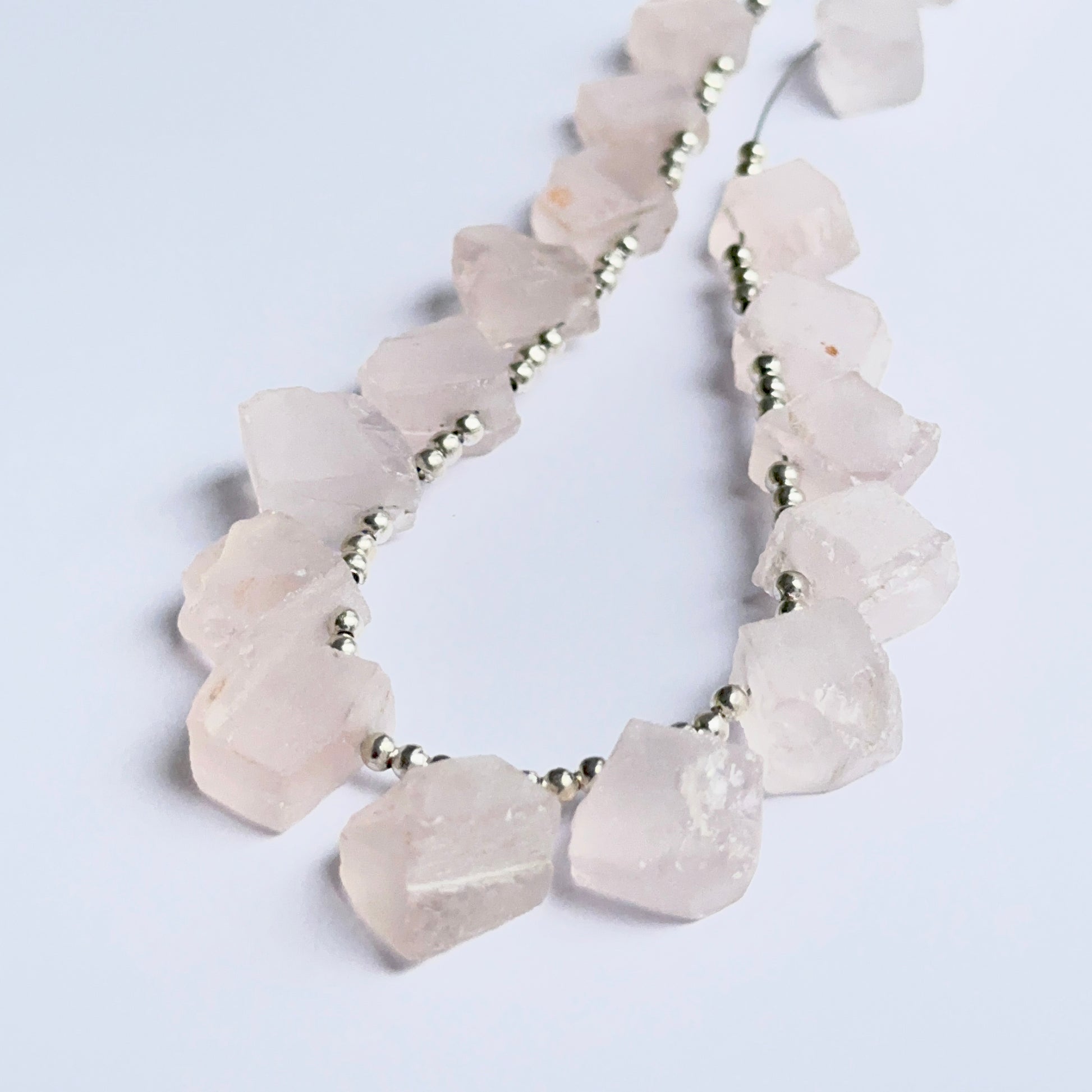 Close‑up of rose quartz rough beads highlighting their organic shape and gentle pastel colour for DIY jewellery.