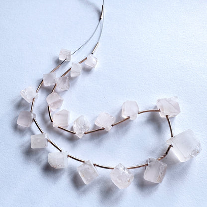 Smooth-cut Rose Quartz beads with subtle shine, laid out to display their organic shapes and quality.
