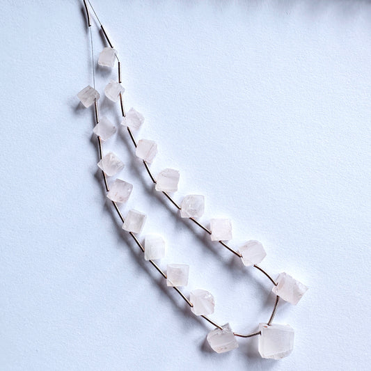 Close-up of pale pink Rose Quartz beads with rough side drill, showcasing natural texture and soft shimmer.