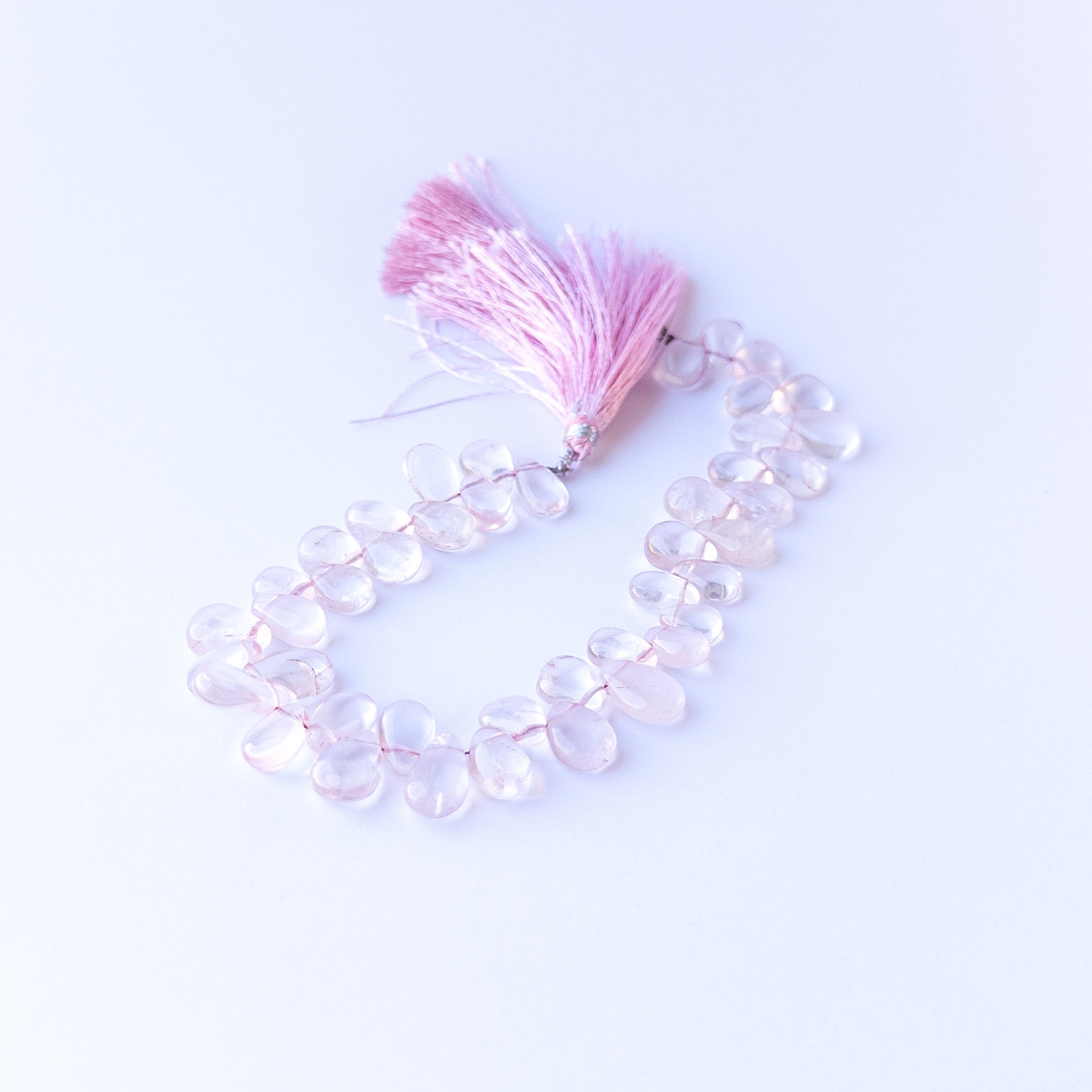 Handmade jewellery components featuring natural rose quartz smooth briolettes with soft tones and polished glow.